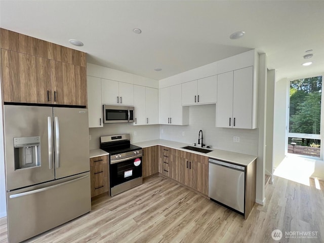 8324 16th Ave NW Unit A, Seattle, WA 98117 - kitchen with stainless steel appliances, a sink, light wood-type flooring, white cabinetry, and recessed lighting
