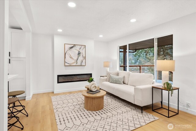 16514 Wallingford Ave N, Shoreline, WA 98133 - living area with light wood-style flooring, a glass covered fireplace, recessed lighting, and baseboards