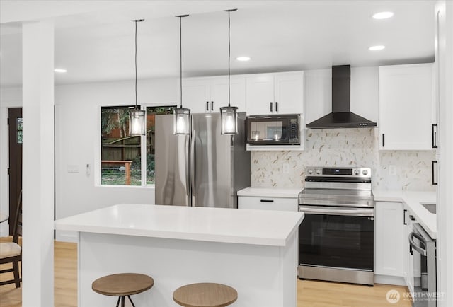 16514 Wallingford Ave N, Shoreline, WA 98133 - kitchen featuring stainless steel appliances, wall chimney range hood, light wood-type flooring, a breakfast bar, and light countertops