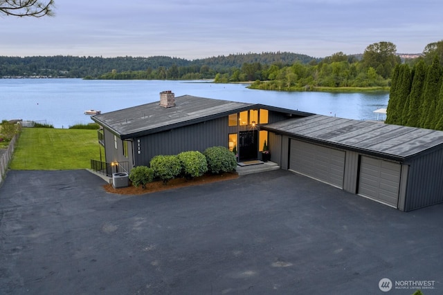 5110 NW Sammamish Rd, Issaquah, WA 98027 - view of front of house with a wooded view, a chimney, a water view, central AC unit, and a garage