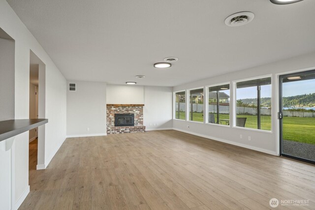5110 NW Sammamish Rd, Issaquah, WA 98027 - unfurnished living room featuring light wood-style floors, baseboards, a brick fireplace, and a water view