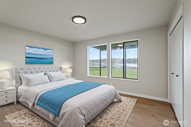 5110 NW Sammamish Rd, Issaquah, WA 98027 - bedroom featuring light wood-style flooring, a water view, baseboards, and a closet