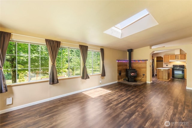 513 346th St E, Roy, WA 98580 - unfurnished living room featuring a wood stove, a skylight, dark wood-style floors, baseboards, and arched walkways