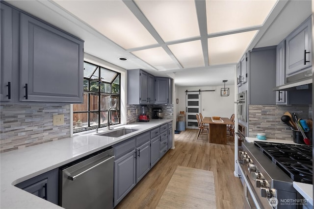 2711 Grampin Ct SE, Olympia, WA 98501 - kitchen featuring appliances with stainless steel finishes, a barn door, a sink, decorative backsplash, and light countertops