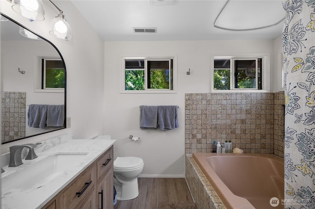 2711 Grampin Ct SE, Olympia, WA 98501 - bathroom with tiled bath, vanity, wood finished floors, toilet, and baseboards