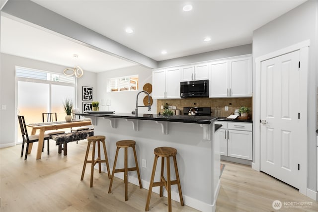 17826 20th Ave SE, Bothell, WA 98012 - kitchen featuring stainless steel microwave, a breakfast bar, decorative backsplash, dark countertops, and white cabinets