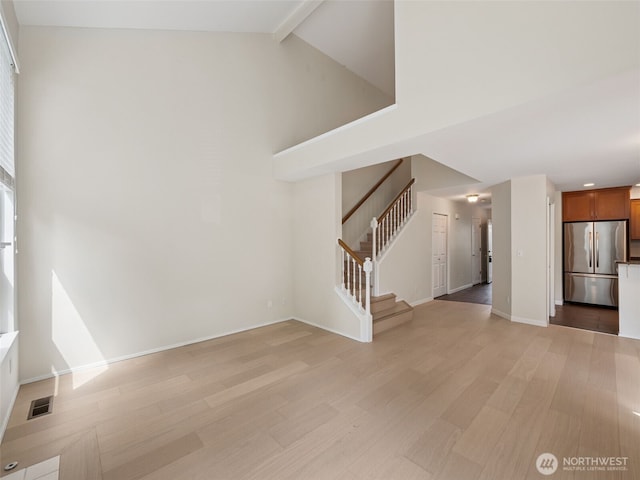23501 112th Ave SE Unit M104, Kent, WA 98031 - unfurnished living room featuring light wood-style flooring, stairs, beam ceiling, high vaulted ceiling, and baseboards