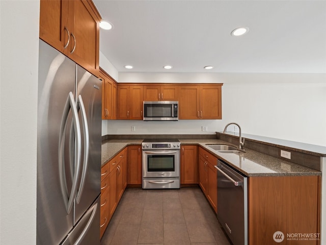23501 112th Ave SE Unit M104, Kent, WA 98031 - kitchen with appliances with stainless steel finishes, a sink, a peninsula, brown cabinets, and dark stone countertops