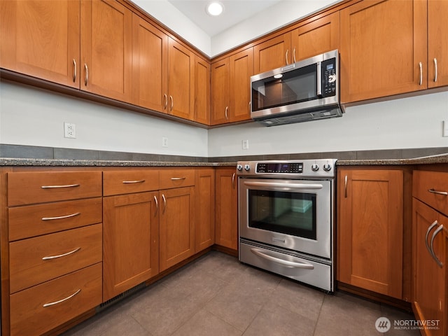 23501 112th Ave SE Unit M104, Kent, WA 98031 - kitchen with stainless steel appliances, brown cabinets, dark tile patterned floors, dark stone counters, and recessed lighting