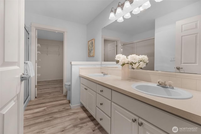 2009 196th St SE Unit G104, Bothell, WA 98012 - bathroom with double vanity, toilet, a shower stall, wood finished floors, and a spacious closet