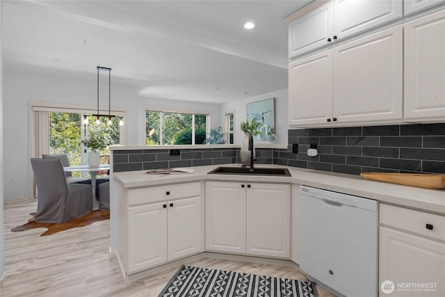 2009 196th St SE Unit G104, Bothell, WA 98012 - kitchen featuring dishwasher, a sink, a peninsula, tasteful backsplash, and white cabinetry