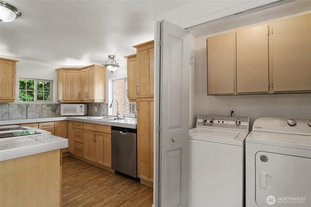 330 Highland Ave, Chelan, WA 98816 - kitchen featuring stainless steel dishwasher, washing machine and dryer, a sink, white microwave, and light wood-style floors