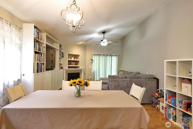 19523 71st Ave E, Spanaway, WA 98387 - dining room with wood finished floors, a tiled fireplace, a chandelier, and a ceiling fan