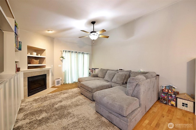 19523 71st Ave E, Spanaway, WA 98387 - living room featuring a tiled fireplace, ceiling fan, wood finished floors, and built in features