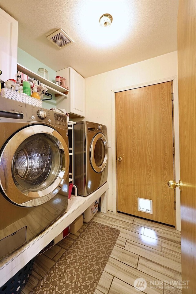 19523 71st Ave E, Spanaway, WA 98387 - laundry room featuring cabinet space, washing machine and dryer, and light wood-type flooring