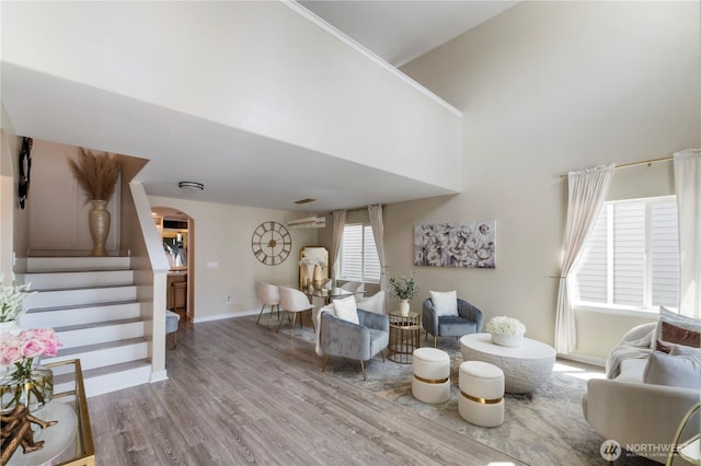 18113 17th Avenue Ct E, Spanaway, WA 98387 - living area featuring arched walkways, wood finished floors, stairway, baseboards, and a towering ceiling