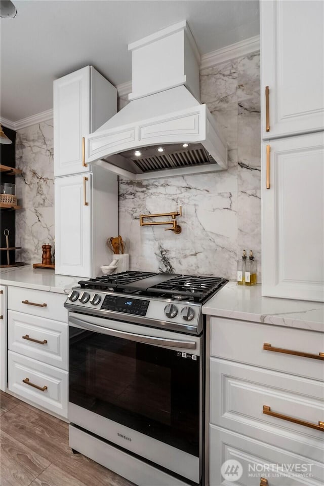 18113 17th Avenue Ct E, Spanaway, WA 98387 - kitchen featuring stainless steel gas range oven, custom exhaust hood, ornamental molding, white cabinets, and tasteful backsplash