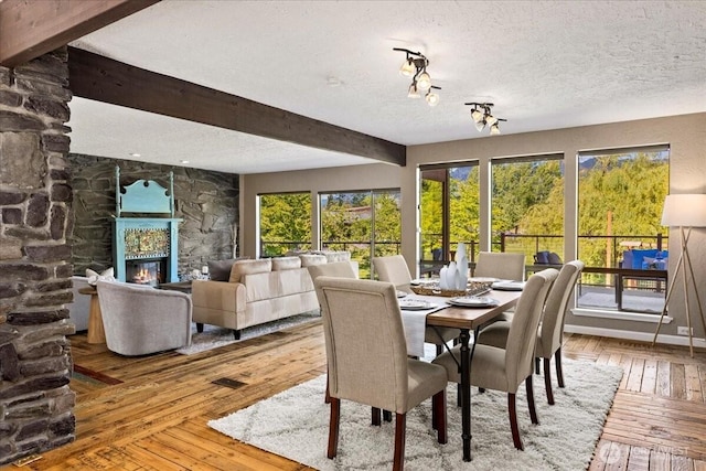 41506 292nd Way SE, Enumclaw, WA 98022 - dining area featuring hardwood / wood-style floors, a stone fireplace, a textured ceiling, and beam ceiling