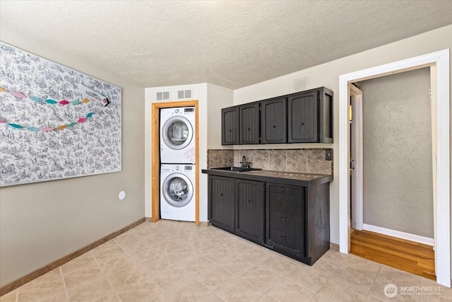 41506 292nd Way SE, Enumclaw, WA 98022 - laundry area featuring stacked washing machine and dryer, cabinet space, light tile patterned flooring, baseboards, and a textured ceiling