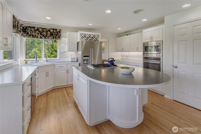 11207 16th St E, Edgewood, WA 98372 - kitchen featuring stainless steel appliances, a sink, a center island, light wood-style flooring, and white cabinetry