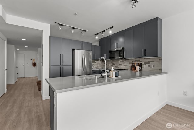 17 W Mercer St Unit 216, Seattle, WA 98119 - kitchen with appliances with stainless steel finishes, a peninsula, light wood-style flooring, tasteful backsplash, and light countertops