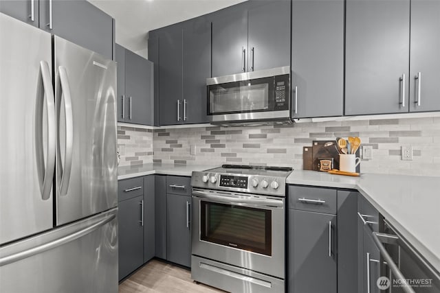 17 W Mercer St Unit 216, Seattle, WA 98119 - kitchen featuring appliances with stainless steel finishes, light countertops, decorative backsplash, light wood-type flooring, and gray cabinetry