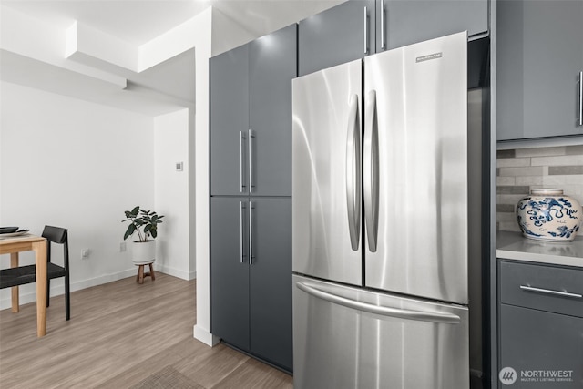 17 W Mercer St Unit 216, Seattle, WA 98119 - kitchen featuring freestanding refrigerator, gray cabinets, light wood-style floors, tasteful backsplash, and baseboards