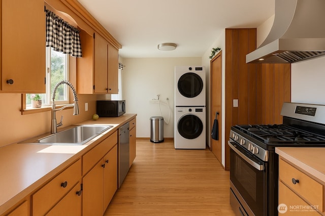 12010 2nd Ave SW, Seattle, WA 98146 - kitchen with stainless steel appliances, wall chimney range hood, estacked washer and dryer, light countertops, and light wood-style flooring