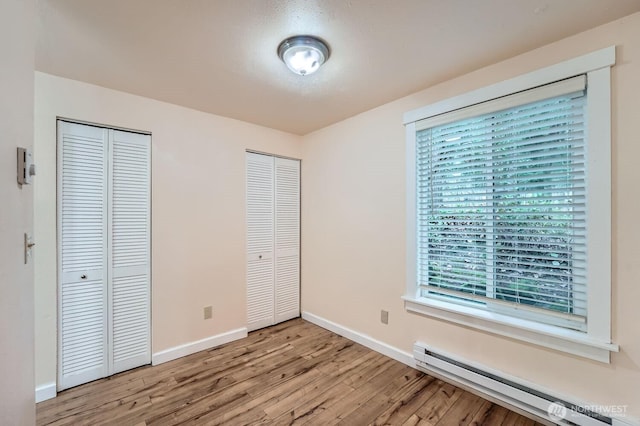4601 SW 320th St Unit K4, Federal Way, WA 98023 - unfurnished bedroom with a baseboard heating unit, multiple closets, light wood-style floors, and multiple windows