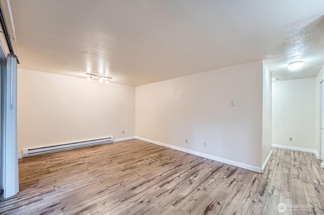 4601 SW 320th St Unit K4, Federal Way, WA 98023 - empty room with baseboard heating, light wood-type flooring, rail lighting, and baseboards