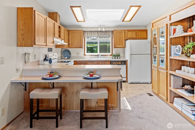 1402 22nd St NE Unit 515, Auburn, WA 98002 - kitchen with white appliances, under cabinet range hood, a peninsula, light countertops, and a breakfast bar