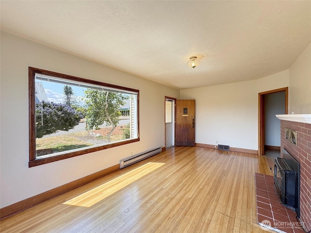 1025 W 6th St, Port Angeles, WA 98363 - unfurnished living room with a baseboard heating unit, hardwood / wood-style flooring, a wood stove, and baseboards