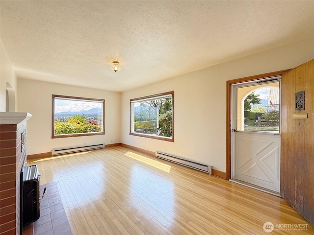 1025 W 6th St, Port Angeles, WA 98363 - unfurnished living room with a baseboard radiator, wood finished floors, a textured ceiling, and baseboards