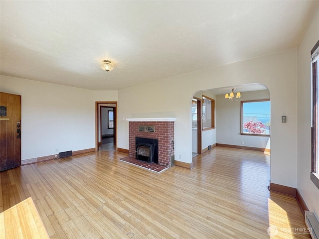 1025 W 6th St, Port Angeles, WA 98363 - unfurnished living room with light wood finished floors, a chandelier, arched walkways, and baseboards