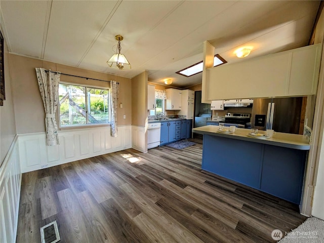 201 Hemlock St, Orcas Island, WA 98245 - kitchen featuring appliances with stainless steel finishes, under cabinet range hood, a peninsula, blue cabinetry, and dark wood-style flooring