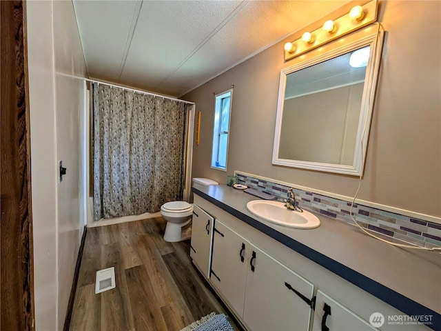 201 Hemlock St, Orcas Island, WA 98245 - full bathroom with wood finished floors, vanity, tasteful backsplash, toilet, and curtained shower