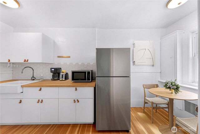 4725 15th Ave NE Unit 37, Seattle, WA 98105 - kitchen with appliances with stainless steel finishes, a sink, light wood-style floors, and tasteful backsplash