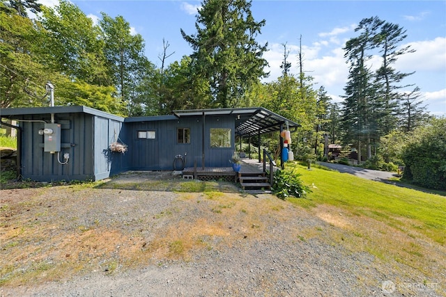 18482 Pull And Be Damned Rd, La Conner, WA 98257 - back of house featuring board and batten siding, a deck, view of wooded area, and a yard
