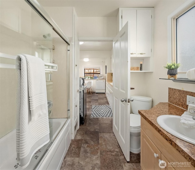 5011 5th Ave NE, Seattle, WA 98105 - bathroom with vanity, stone finish flooring, bath / shower combo with glass door, and toilet
