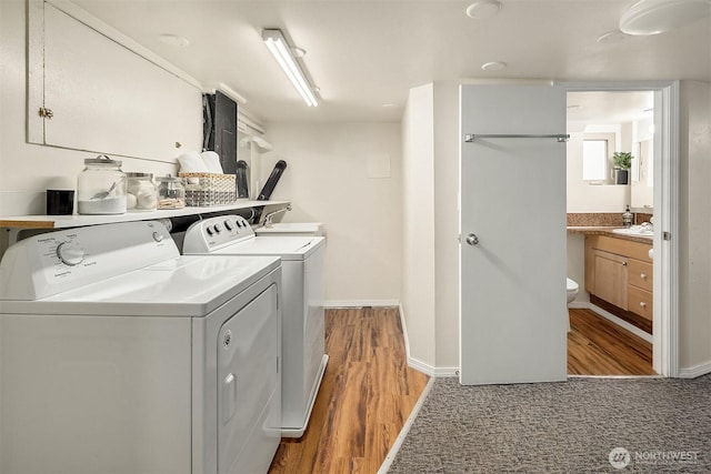 5011 5th Ave NE, Seattle, WA 98105 - laundry room with light wood-style flooring, washer and clothes dryer, a sink, and baseboards
