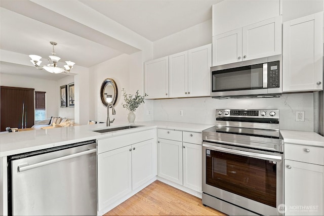 11864 NE 162nd Ln Unit 11-2, Bothell, WA 98011 - kitchen featuring appliances with stainless steel finishes, a sink, a peninsula, a chandelier, and light countertops