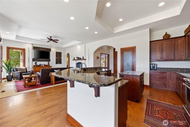 134 Borealis Ln, Manson, WA 98831 - kitchen featuring a raised ceiling, a spacious island, arched walkways, a kitchen bar, and a ceiling fan