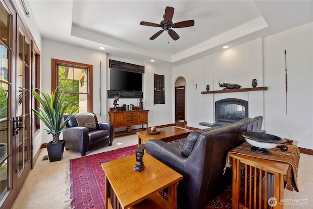 134 Borealis Ln, Manson, WA 98831 - carpeted living room with a raised ceiling, arched walkways, baseboards, a multi sided fireplace, and a ceiling fan