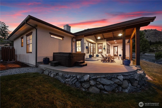 134 Borealis Ln, Manson, WA 98831 - back of property featuring a hot tub, a patio area, a chimney, and stucco siding