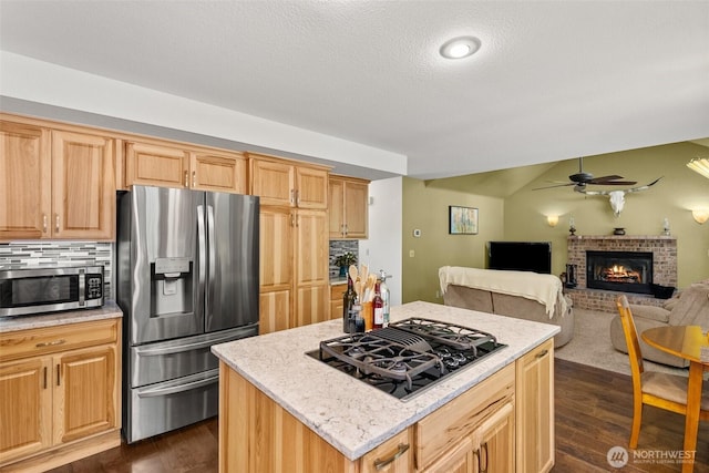 1228 Tabitha Ct NW, Olympia, WA 98502 - kitchen featuring stainless steel appliances, a fireplace, dark wood-type flooring, ceiling fan, and a kitchen island