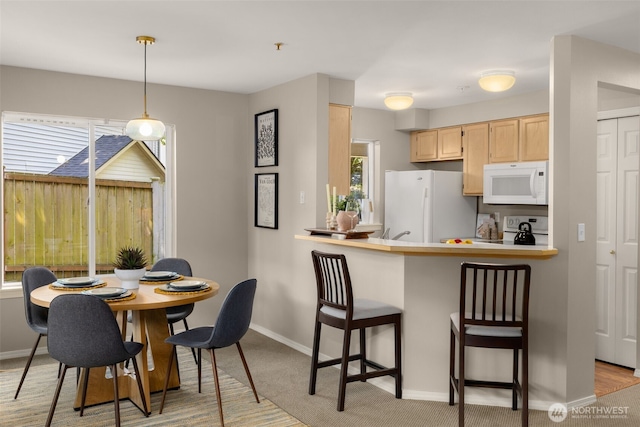 730 112th St SW Unit G106, Everett, WA 98204 - kitchen with white appliances, light brown cabinets, a breakfast bar, baseboards, and light colored carpet