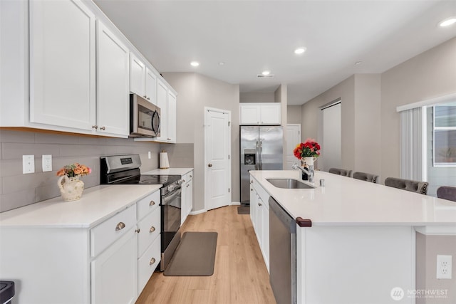 15834 205th Ave E, Bonney Lake, WA 98391 - kitchen featuring appliances with stainless steel finishes, a sink, light wood-type flooring, a center island with sink, and white cabinets