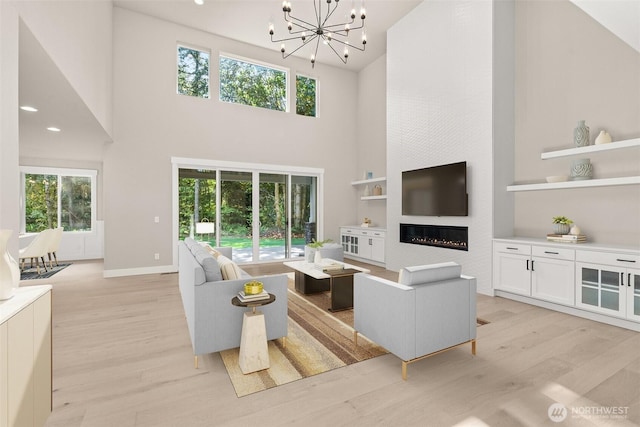 2446 64th Ave NW, Olympia, WA 98502 - living area with light wood-style flooring, a towering ceiling, a chandelier, built in features, and baseboards