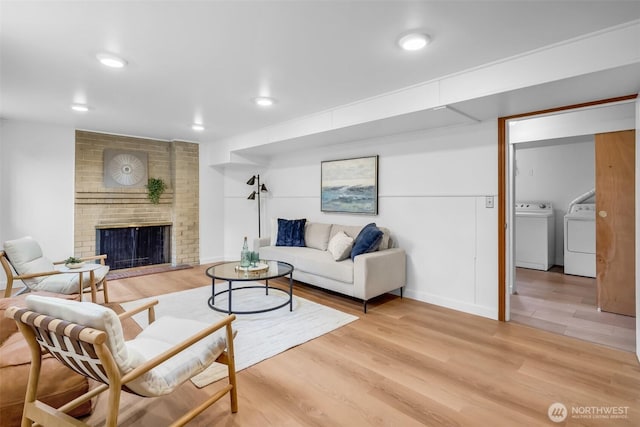 4619 SW Genesee St, Seattle, WA 98116 - living room featuring washing machine and dryer, light wood-type flooring, a brick fireplace, and recessed lighting