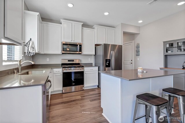 924 Livernash St, Buckley, WA 98321 - kitchen with appliances with stainless steel finishes, a sink, a breakfast bar area, white cabinetry, and recessed lighting
